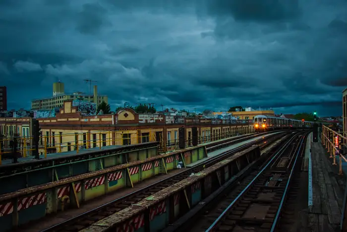 This is a photo of a subway train pulling into an above ground station just before a storm.